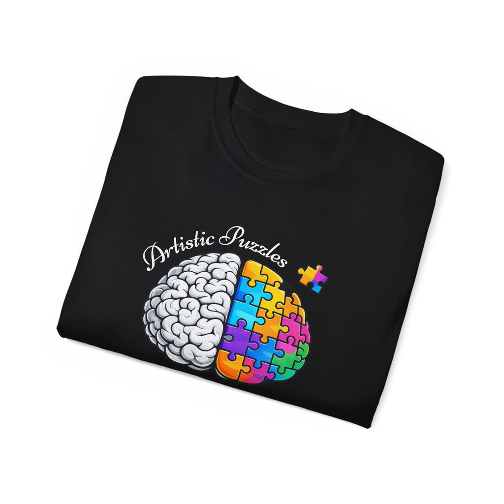 Folded Artistic Puzzles 'Piece By Piece' Signature Brain Tee by Printify featuring a vibrant split brain design integrated with puzzle pieces on a black fabric.